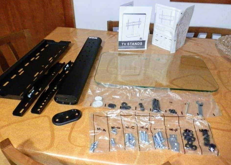 Rilevatore di TV con supporto e accessori, componenti per montaggio, istruzioni e strumenti per assemblare supporto TV in casa. Attrezzi e parti di ricambio per montaggio stabile e sicuro.