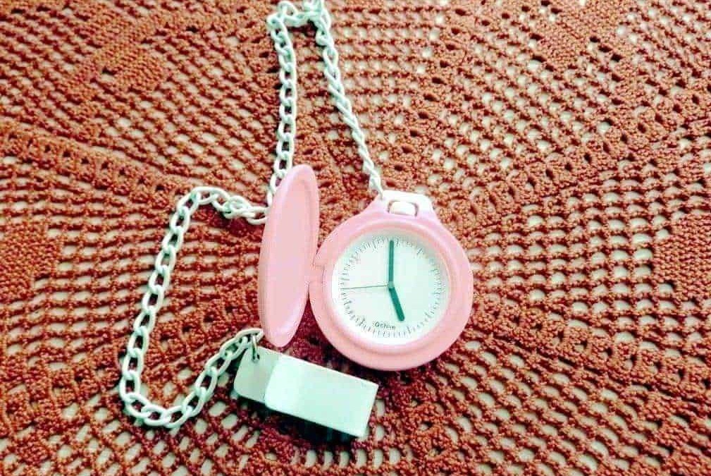 Orologio da cucina rosa con catena, posato su una superficie di feltro arancione rugoso, simbolo di puntualità e tempo per il blog Appunti Sul Blog.