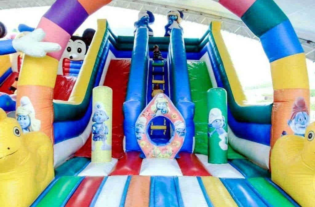 Colorato castello gonfiabile con scivolo, decorato con personaggi dei cartoni animati, ideale per feste di compleanno e eventi per bambini, zone di divertimento in inflabile per bambini.