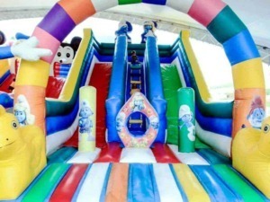 Colorato castello gonfiabile con scivolo, decorato con personaggi dei cartoni animati, ideale per feste di compleanno e eventi per bambini, zone di divertimento in inflabile per bambini.