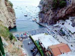 Spiaggia con barche e scogliere a Positano, Costa Amalfitana, vista dall'alto con ristoranti e negozi sul lungomare. Perfetta destinazione turistica per vacanze al mare e relax.