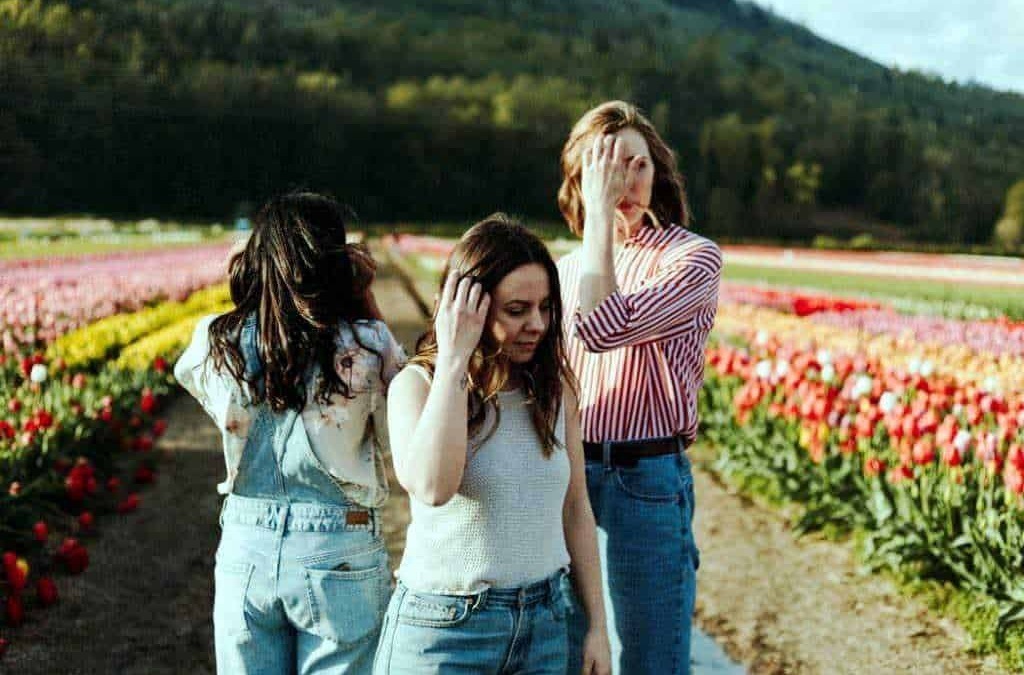 Fiori di tulipani in un campo primaverile con tre donne che si proteggono dal sole, atmosfera rilassante e scenografia naturale, perfetta per blog di lifestyle e viaggi.
