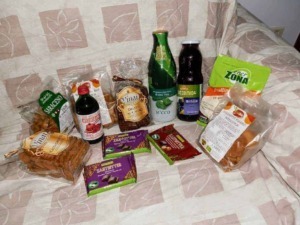 Pane integrale e prodotti da forno biologici, snack salutari, succhi di aloe vera e integratori naturali su un letto con copriletto a fantasia; prodotti alimentari naturali e biologici.