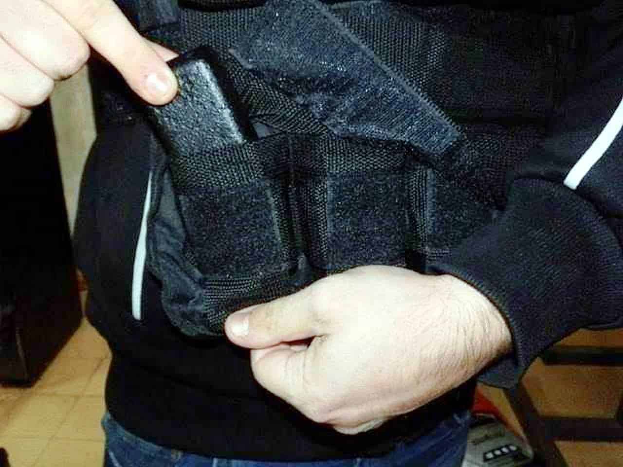 Borsa sportiva nero e grigia in tessuto resistente con tasche interne e zip, uomo che indossa abbigliamento casual, focus sulla apertura della tasca della borsa.
