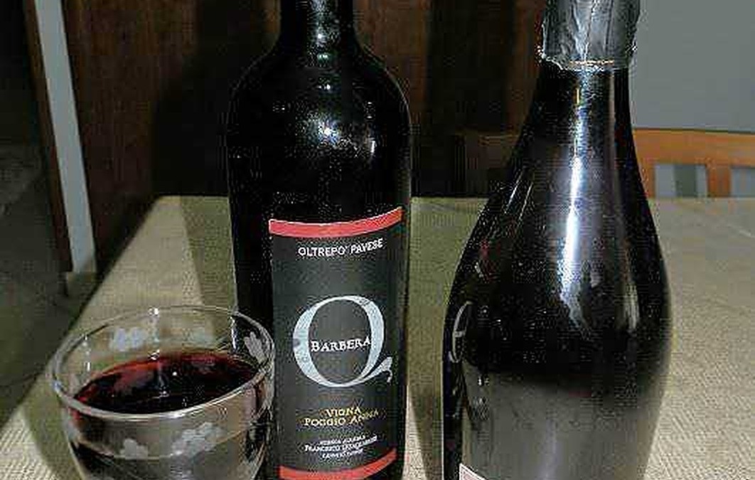 Vino rosso e spumante su tavolo con bottiglie di vino e calice pieno, atmosfera elegante per degustazione di vini italiani.
