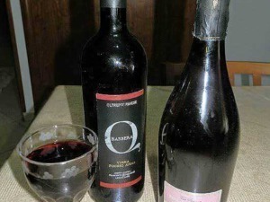 Vino rosso e spumante su tavolo con bottiglie di vino e calice pieno, atmosfera elegante per degustazione di vini italiani.