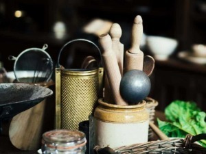Set di utensili da cucina in legno e metallo, toni caldi e vintage, perfetti per cucina casalinga o artigianale, con ciotola, grattugia e coltelli.