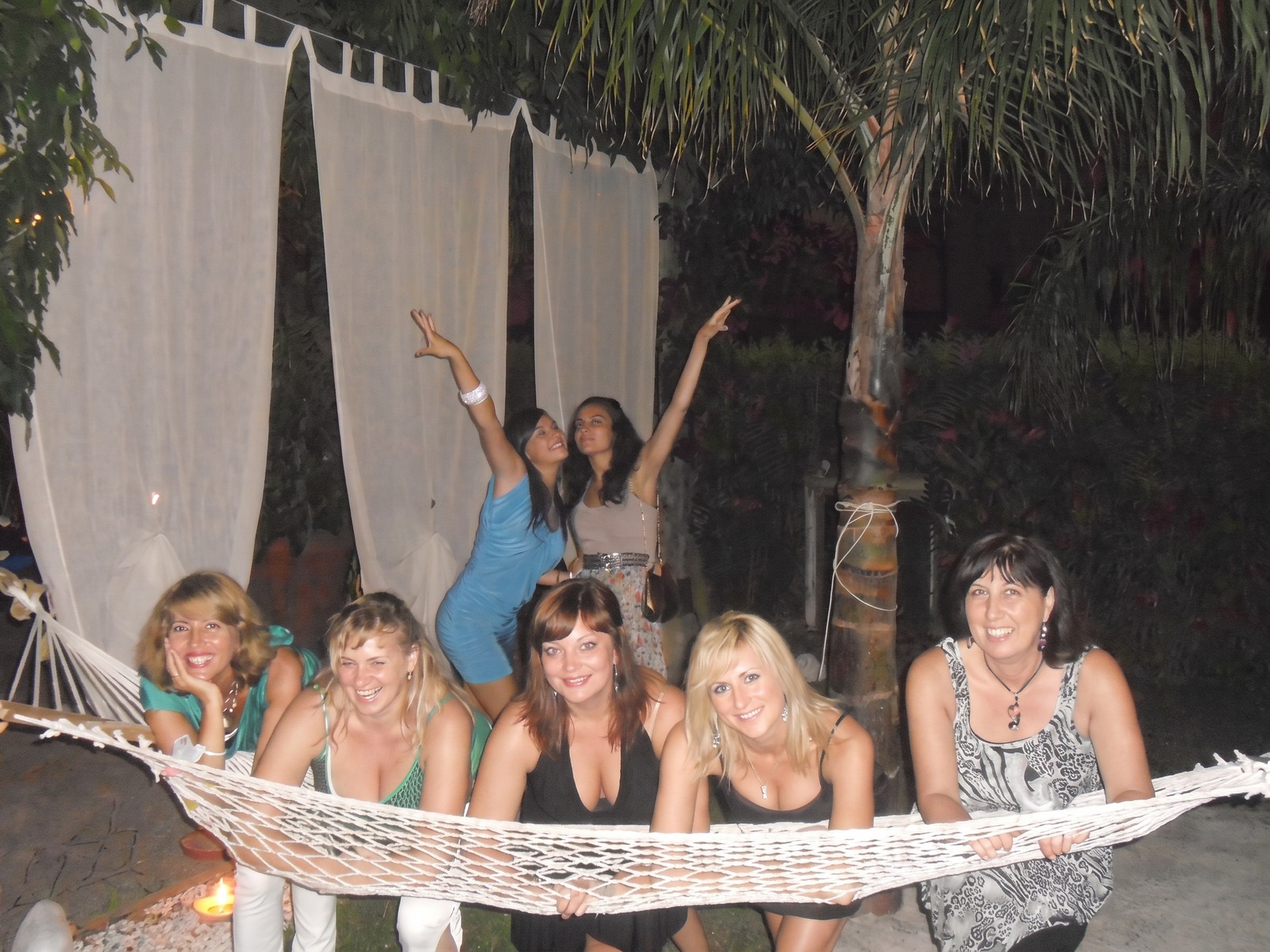 Persone che si divertono all'aperto durante una festa serale con atmosfera festosa e spensierata, riprese con un dispositivo fotografico digitale.