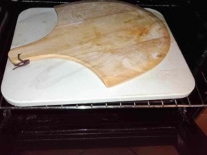 Pietra refrattaria pizzastein: Tagliere in legno su forno con piastra in ceramica, oggetto per preparare cibi, cucina italiana, utensile di cucina tradizionale, attrezzature da cucina rustiche e artigianali.