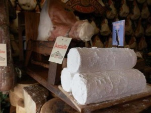 Formaggio fresco di mucca su scaffale in negozio di salumi e formaggi italiani, stagionature e prodotti tipici.