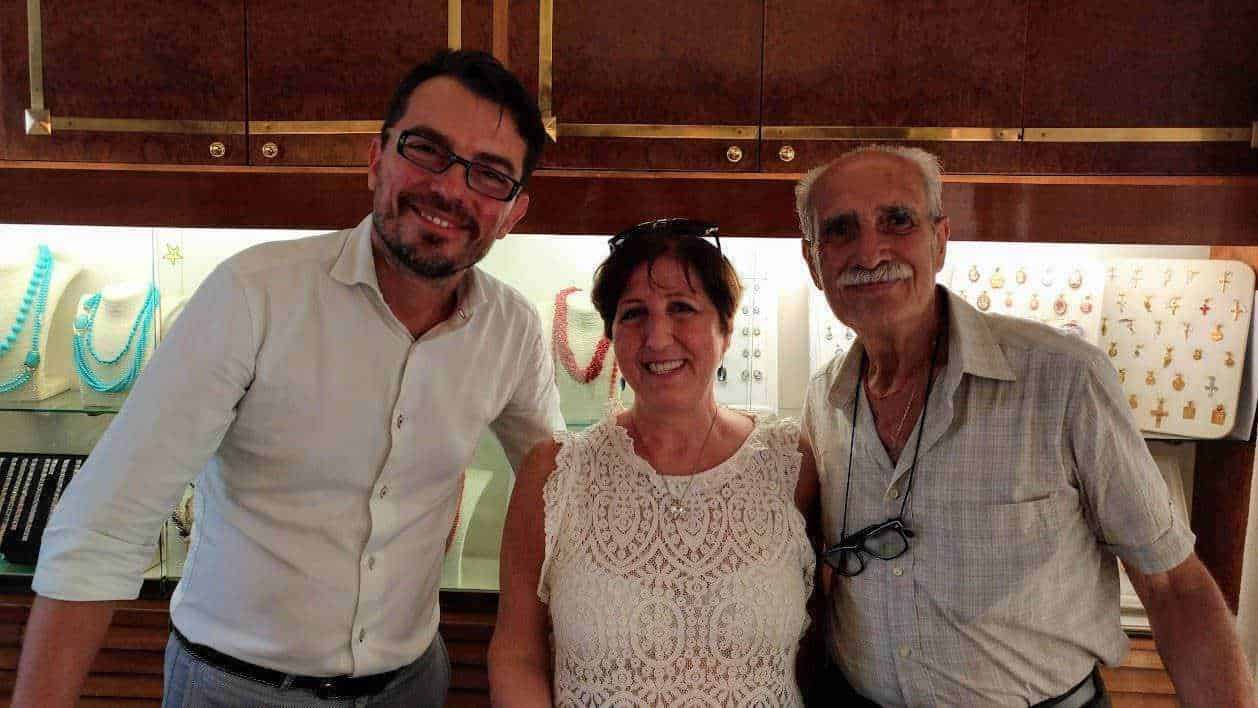 Eleganti uomini e donna sorridenti in negozio di gioielli con collezioni di collane e orecchini in esposizione.