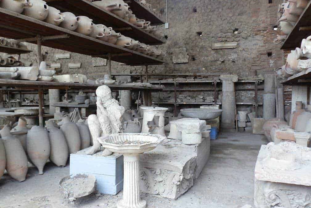 Ex voto di antichi reperti archeologici, statue, urne e frammenti di epoca romana esposti in un laboratorio di restauro archeologico.