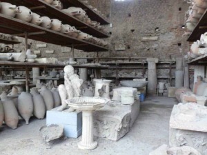 Ex voto di antichi reperti archeologici, statue, urne e frammenti di epoca romana esposti in un laboratorio di restauro archeologico.