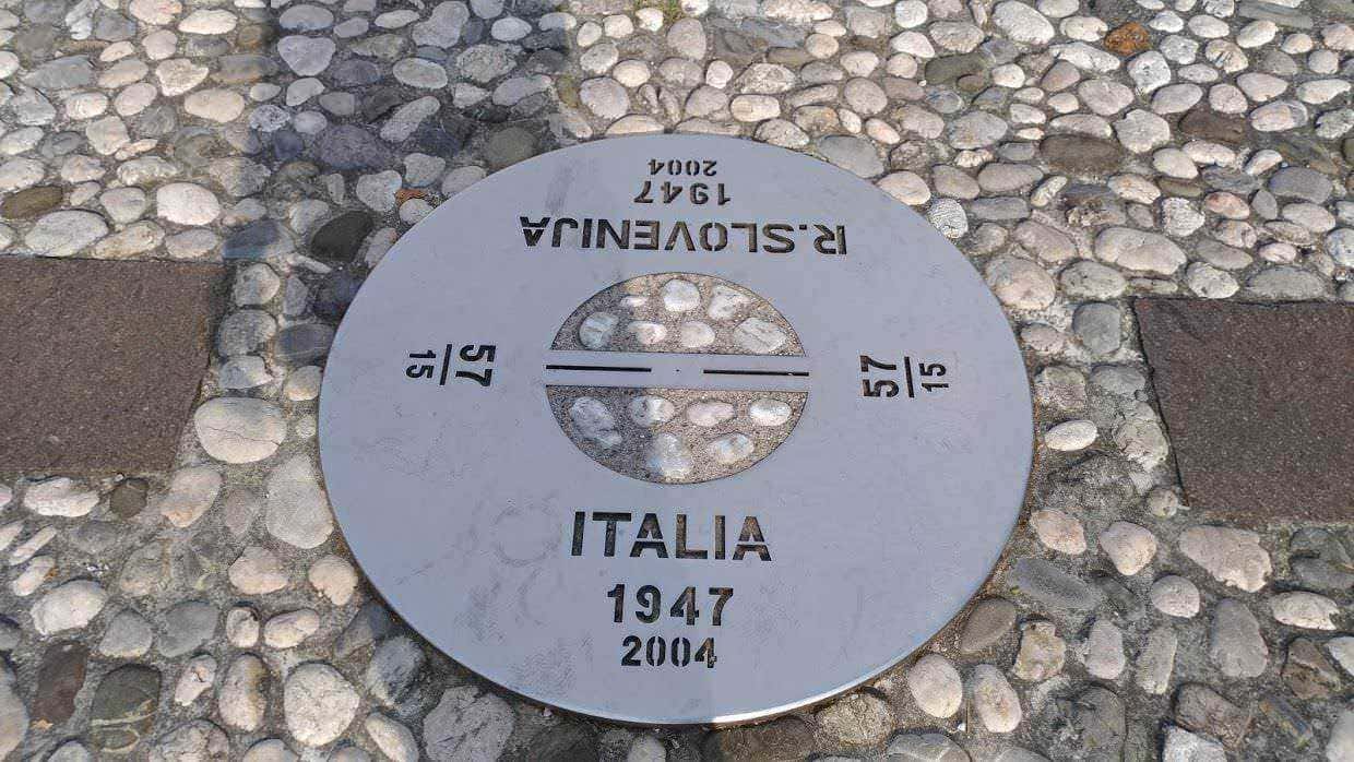 Piastra commemorativa Italia 1947-2004, simbolo di unità e memoria storica, situata su lastra di pietra mista a ciottoli, rappresenta un punto di riferimento culturale e storico in Italia.
