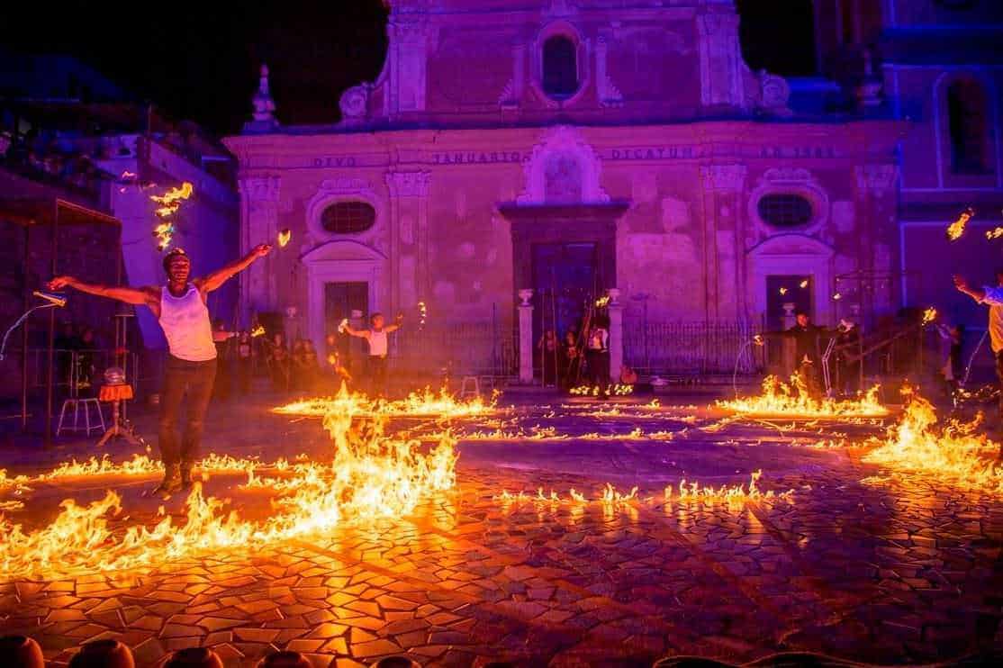 Splendida rappresentazione con luci e fuochi d'artificio sulla piazza di notte, con una chiesa storica sullo sfondo, che crea un'atmosfera magica e suggestiva, ideale per eventi e festività.