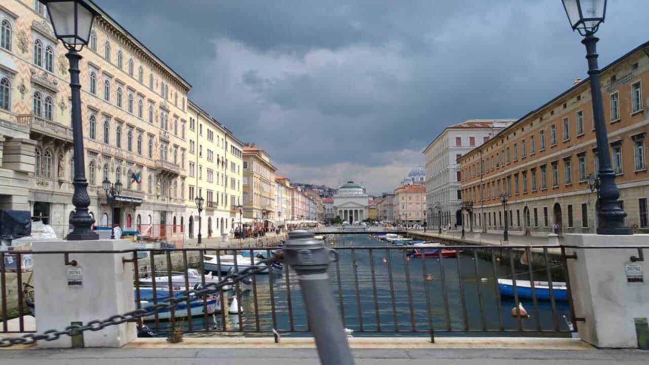 Vicolo con vista sul Canale, con edifici storici e barche attraccate, sotto un cielo nuvoloso