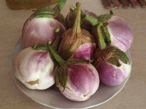 Pomodori di tondo di varie dimensioni con colore rosa e verde, presentati in una ciotola su un tavolo di legno, pronti per essere mangiati o usati nella cucina italiana.