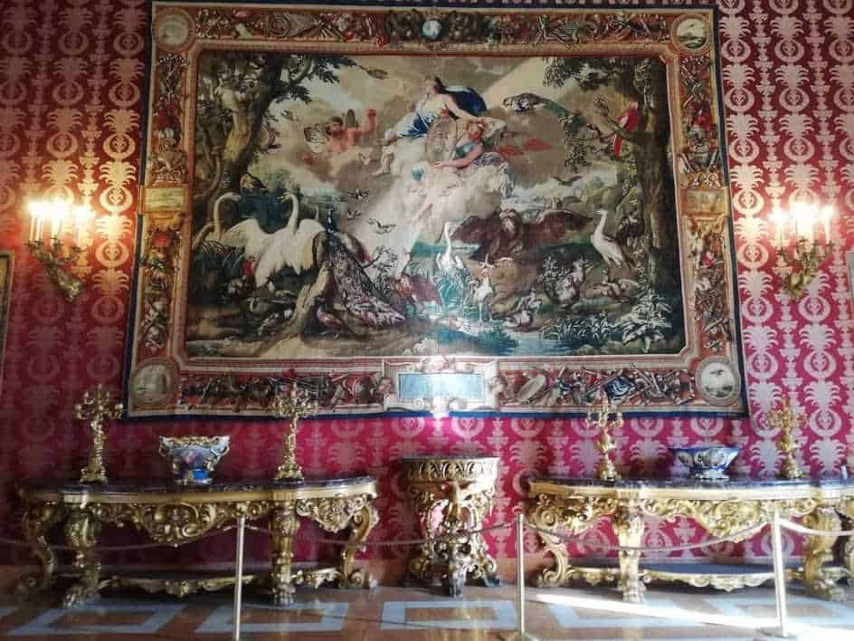 Lusso e arte in uno stile barocco con grande arazzo con figure mitologiche e ornamenti dorati, creando un ambiente elegante e storico.