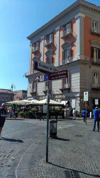 Stazione di Piazza del Duomo con negozi e caffè all'aperto, civico storico e traffico pedonale intenso. Atmosfera urbana vivace e architettura classica italiana