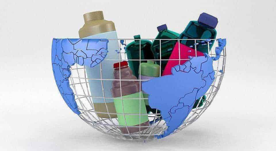 Bombole di plastica all'interno di una ciotola con mappa del mondo in plastica, simbolo di rifiuti e inquinamento ambientale, focus sulla gestione dei rifiuti plastici e sul riciclo.