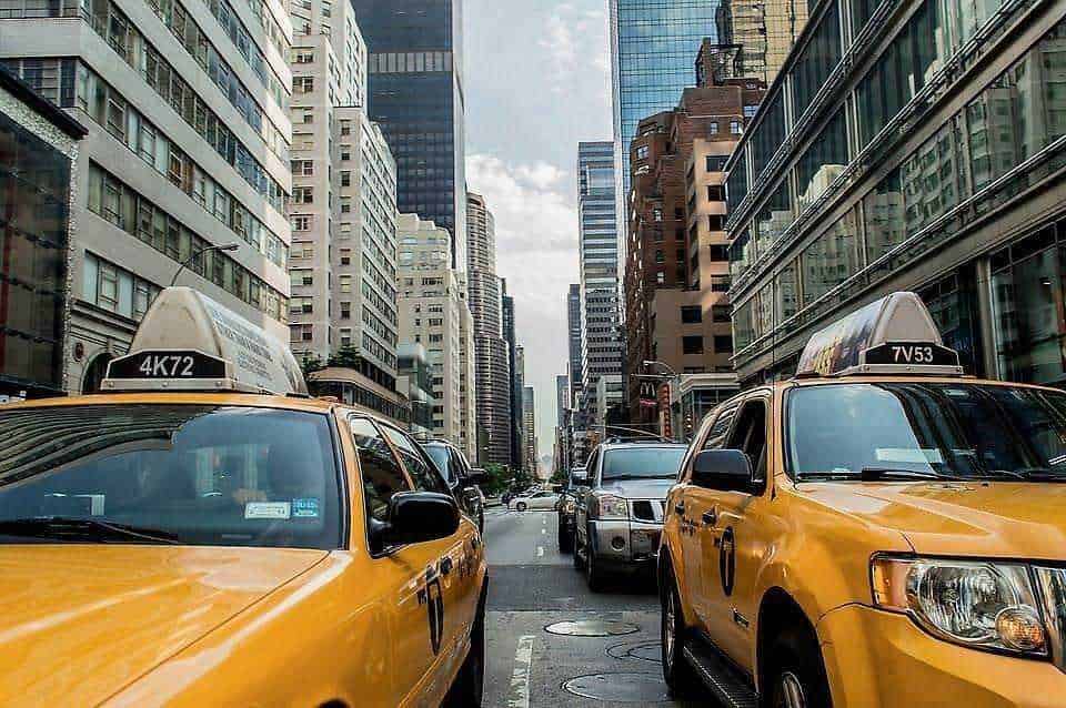 Yellow taxis in New York City bustling street with tall skyscrapers, urban transportation, city life, and iconic yellow cabs.