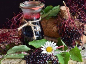 Osco impasto di sambuco, fiori di camomilla e un barattolo di sciroppo di sambuco fatto in casa, elementi naturali e tradizionali per ricette e rimedi casalinghi, in stile rustico e autentico.