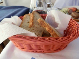 Pane casereccio in cestino con vino rosso e piatto di carne, stile italiano.