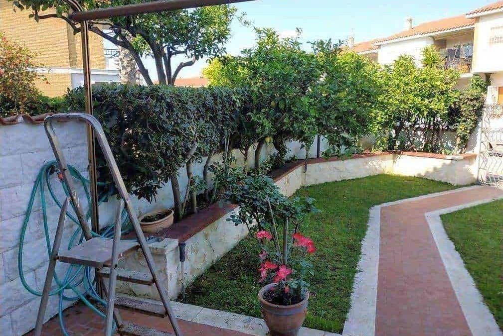 Faro da giardino con piante e siepi, spazio esterno ben curato con vialetto in pietra, ambiente tranquillo e verde.