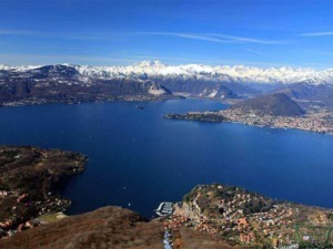 Lago di Garda con le Alpi innevate sullo sfondo, vista panoramica da un’altura, aree residenziali e natura, ideale per appunti sul blog su viaggi, natura e paesaggi italiani.