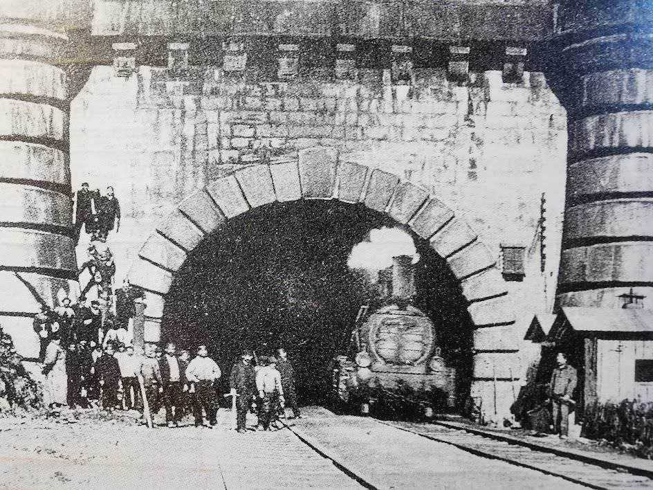 Vapore train che entra in galleria storica, trilogia ferroviaria antica, costruzione di tunnel, viaggio in treno, trasporto ferroviario storico, patrimonio industriale.