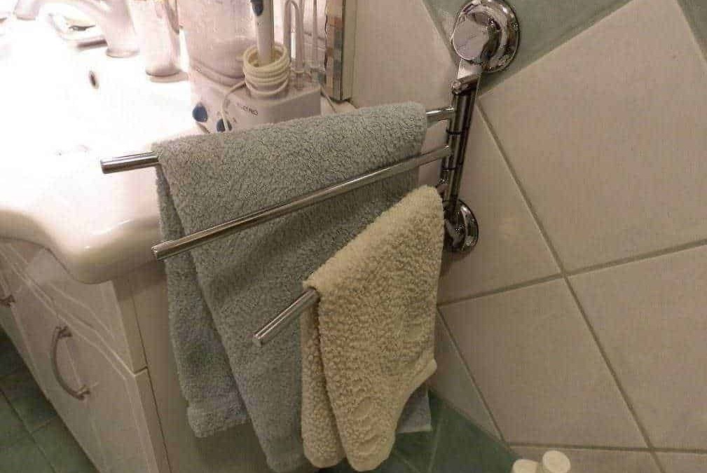 Asciugamani da bagno su portasciugamani in bagno, oltre a asciugamani colorati, in ambiente domestico, accanto a lavabo e prodotti per la cura personale.