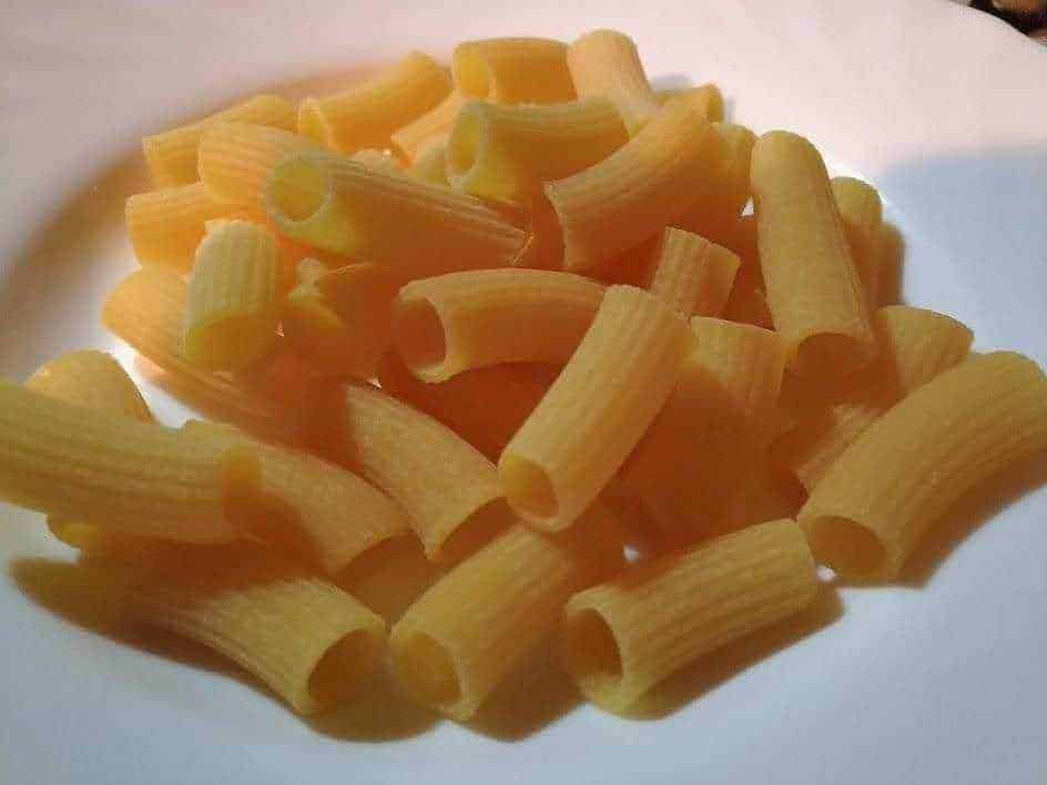 Pasta fresca con ragù di carne e verdure, piatto tradizionale italiano, cucinato e servito in un piatto decorato con fiore e colori vivaci, forchetta a fianco, atmosfera casalinga e autentica.