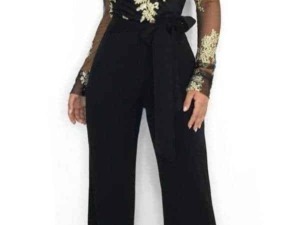 Elegante donna in tuta nera con ricami dorati e dettagli in pizzo, look sofisticato per occasioni speciali.
