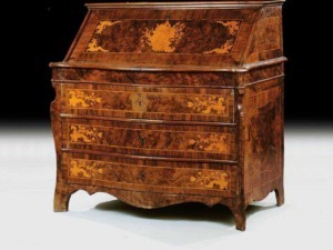 Antico scrittoio in legno pregiato con intricati intarsi artistici e dettagli decorativi, esempio di abilità artigianale e stile storico. Perfetto complemento d'arredo raffinato per ambienti classici.