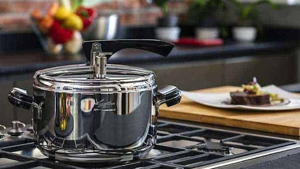 Pentola in acciaio inox su piano cottura con piatto con torta al cioccolato e decorazioni, cucina moderna, cucina casalinga, utensili da cucina, ricette dolci.
