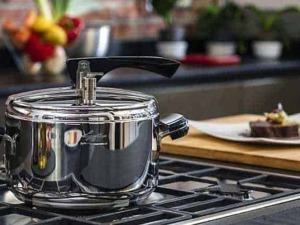 Pentola in acciaio inox su piano cottura con piatto con torta al cioccolato e decorazioni, cucina moderna, cucina casalinga, utensili da cucina, ricette dolci.