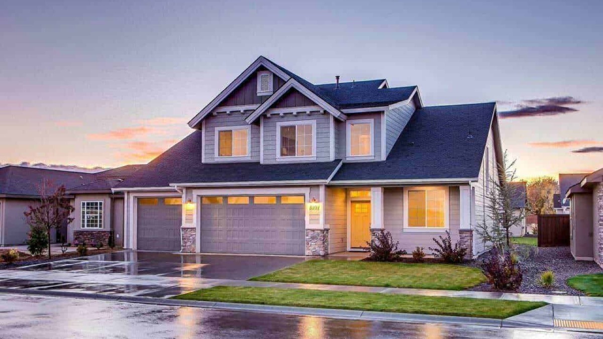 Elegante casa moderna con garage a doppia porta, illuminata dal tramonto, sotto un cielo sereno, in un quartiere residenziale ben curato.