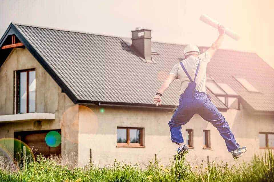 Come migliorare l’isolamento termico della casa 2 Isolamento termico: Ruscello di edilizia, uomo con casco che salta su un prato davanti a una casa in costruzione, lavoro edilizio, ristrutturazione abitativa, edilizia moderna, appunti sul blog.