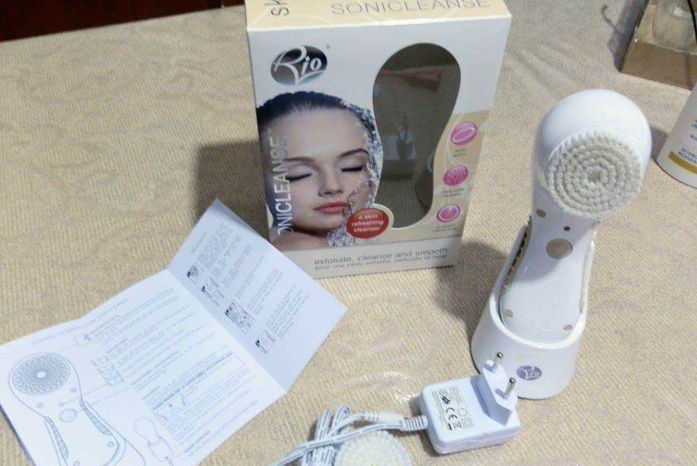 Rimuovere trucco con spazzola faciale elettrica, dispositivo di pulizia della pelle con corpo bianco, istruzioni e scatola originale sul tavolo.