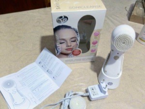 Rimuovere trucco con spazzola faciale elettrica, dispositivo di pulizia della pelle con corpo bianco, istruzioni e scatola originale sul tavolo.