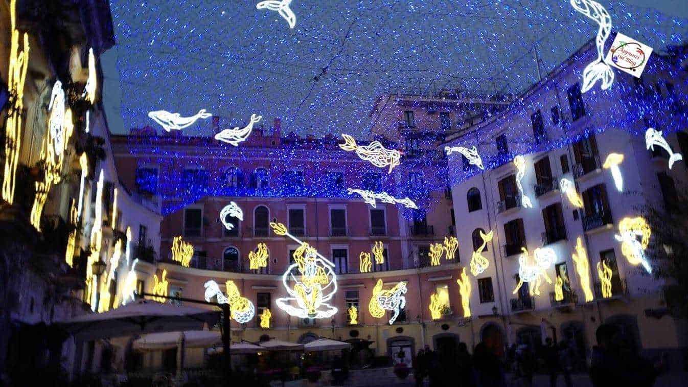 Mercatini di natale: Vita luminoso natalizio con luci decorative di cavalli e figure di Natale, illuminazione urbana di notte, atmosfera festiva, decorazioni di luci appese nel centro storico, evento di Natale a tema equino.
