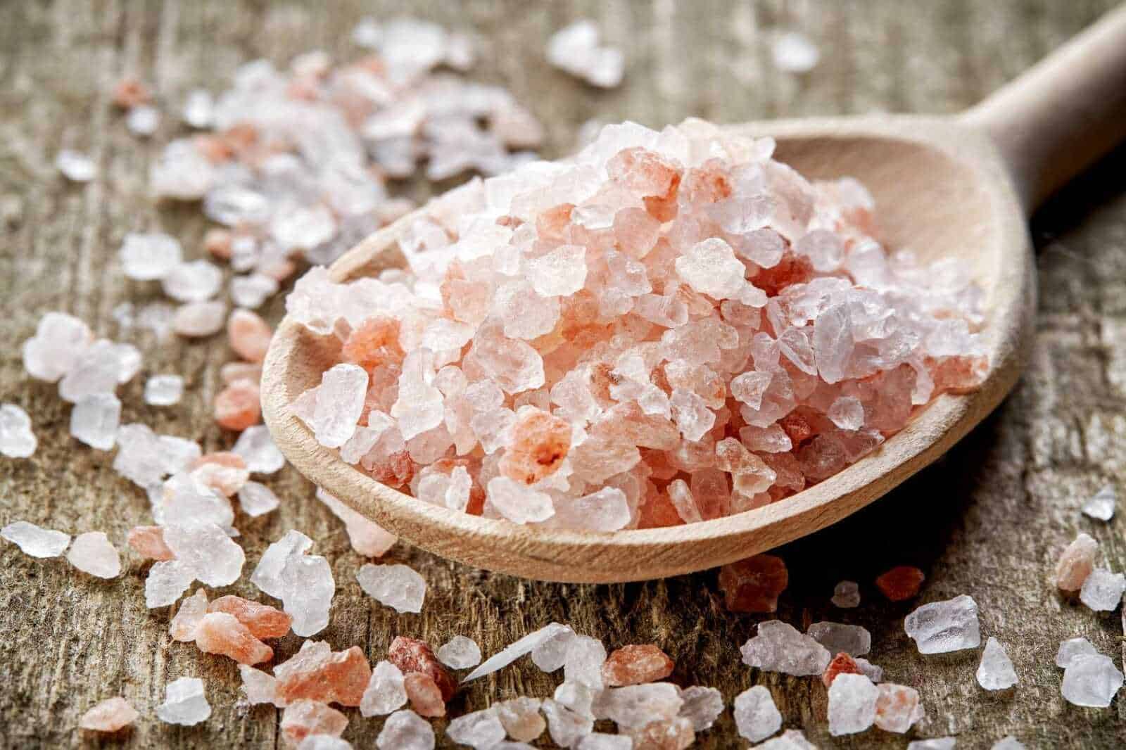 Sale rosa dell'Himalaya sulla cucchiaiata di legno, sale naturale e salgemma rosa, prodotto alimentare salutare, condimento naturale per cucina sana.