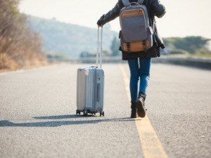 Valigia trolley e zaino da viaggio su strada aperta in campagna, concetto di viaggio avventura, trasporto leggero, vacanze all'aperto, preparativi per viaggio, escursione estiva, itinerario turistico.