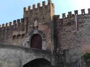 Castello medievale in pietra con torre e mura difensive, ingresso in stile storico, situato in un paesaggio italiano, perfetto esempio di architettura antica e patrimonio culturale.