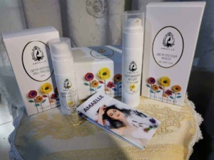 Crema antirughe e cosmetici naturali Amaelle con confezioni eleganti e fiori colorati, sulla tavola decorata, ideale per cura della pelle e routine di bellezza.