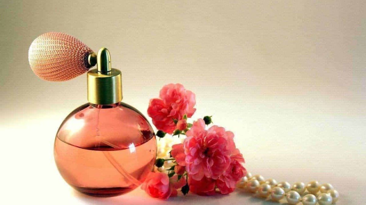 Fragranza floreale con bouquet di fiori rosa, profumo femminile, bottiglia di profumo elegante, accessori moda come perle e fiori, atmosfera di raffinatezza e stile.