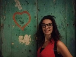 Abbraccio tra due persone in un ambiente urbano con pareti in legno verde e scritte, atmosfera calda e conviviale.