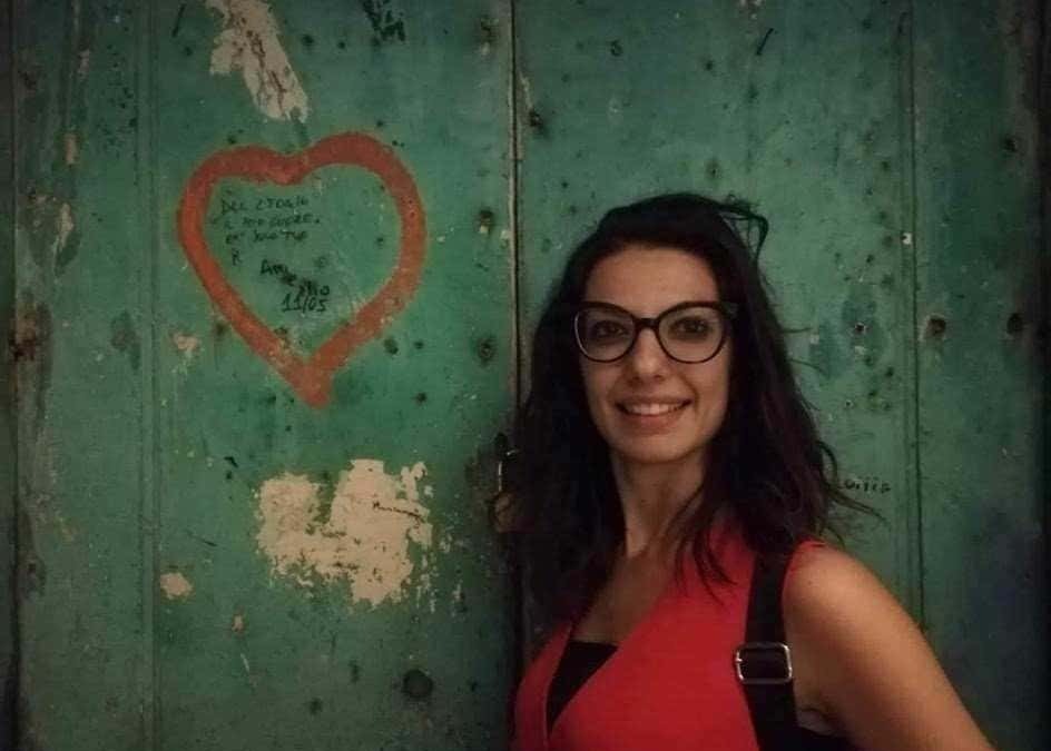 Abbraccio tra due persone in un ambiente urbano con pareti in legno verde e scritte, atmosfera calda e conviviale.