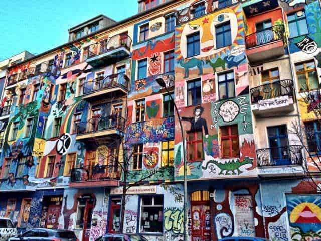 Amanti dell'Arte visiva, scopri 12 città culturali 7 Colorato murale di strada su un edificio a più piani con arte urbana, graffiti e dipinti vivaci che decorano tutta la facciata, creando un ambiente artistico e dinamico.