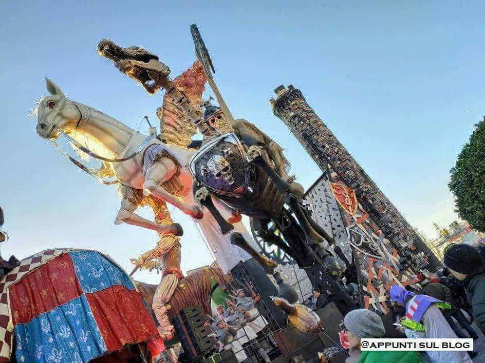 Cavallo di cartapesta e figure di carnevale in una festa tradizionale. Automodelli colorati e decorazioni elaborate creano un'atmosfera festosa e vivace durante l'evento.